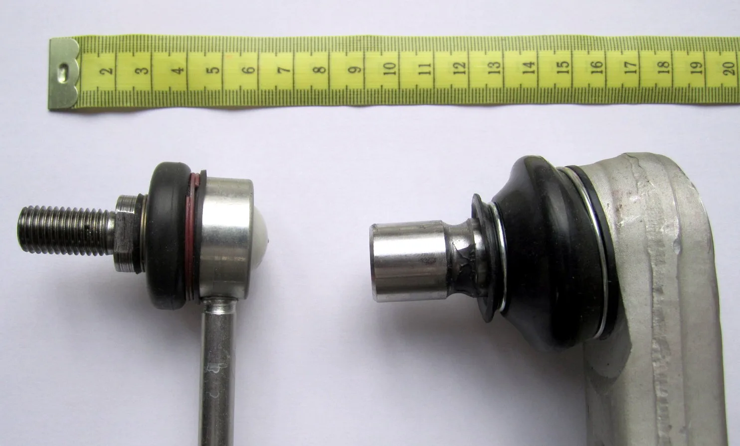 Two removed suspension ball joints beside a measuring tape