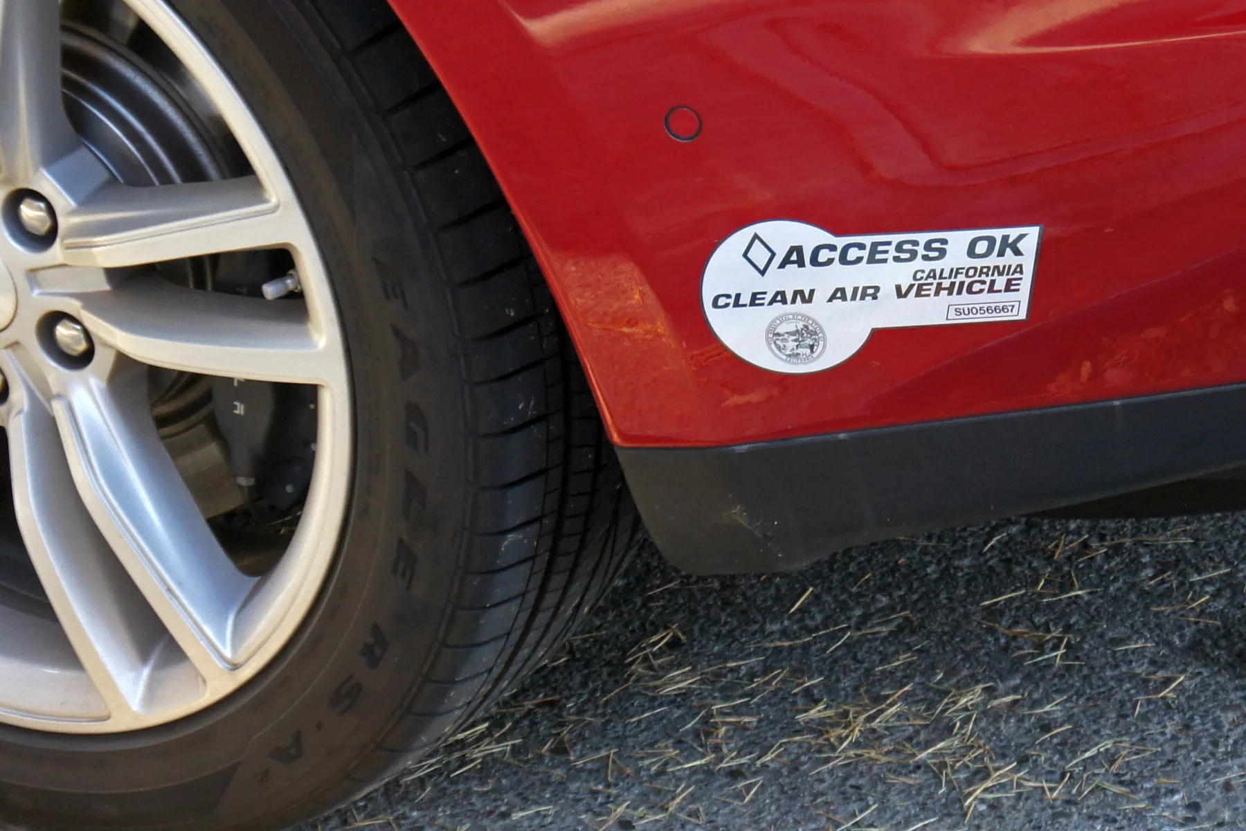 White California Clean Air Vehicle decal on a red car near the rear wheel