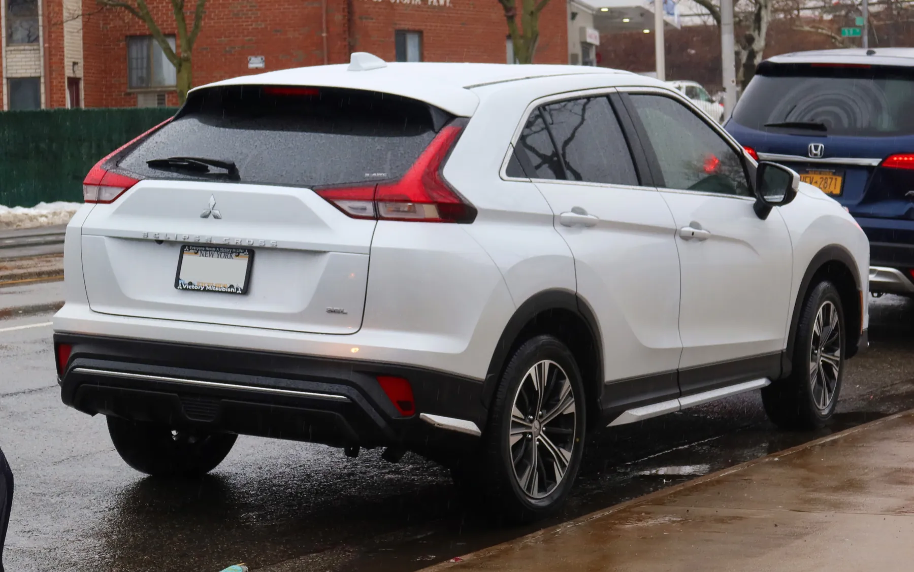 Rear view of a 2022 Mitsubishi Eclipse Cross SEL with a high-mounted stop lamp at the top of the rear glass, lamps to either side, and the three-diamond emblem, Eclipse Cross lettering, and SEL and S-AWC badges on the gate