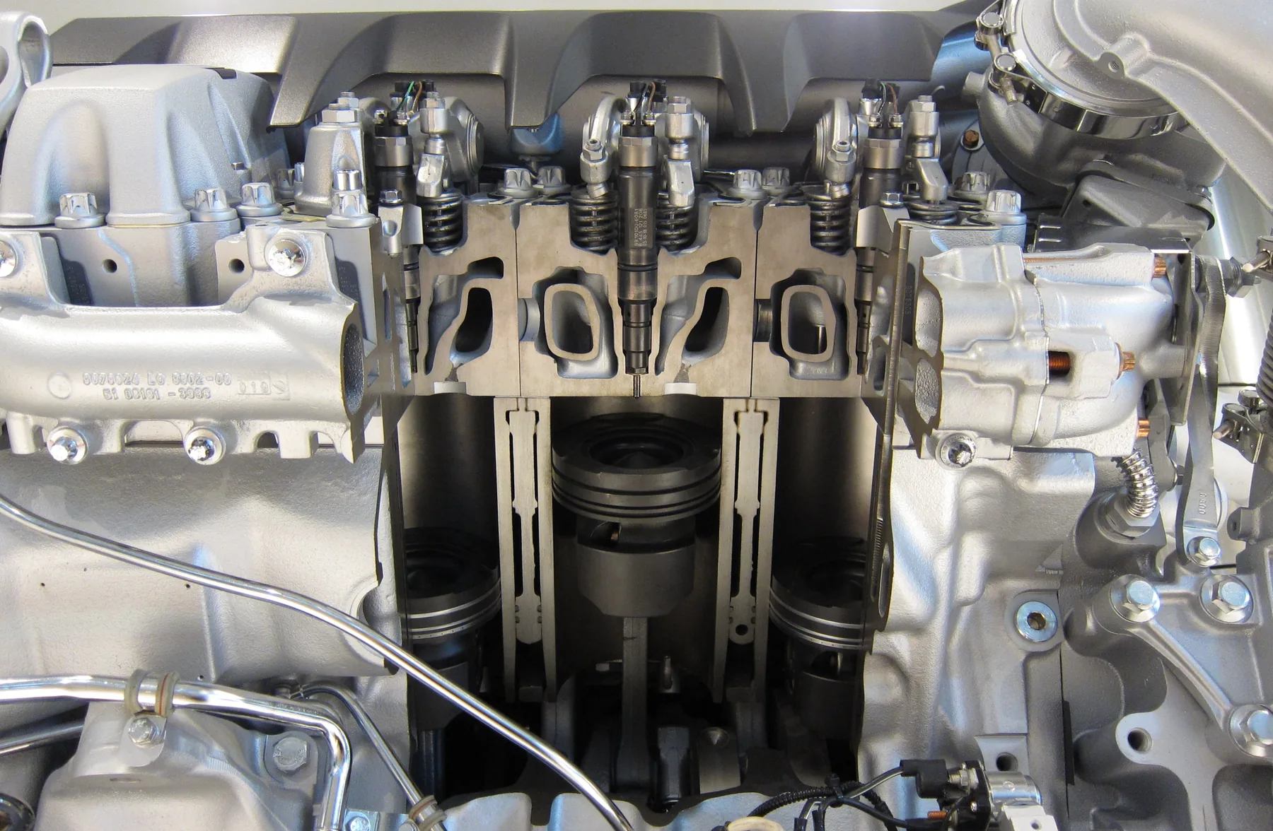 Diesel-engine cutaway showing the cylinder head above the block and opened cylinders
