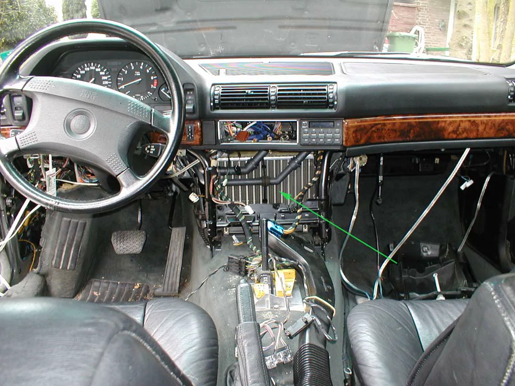 Partly dismantled dashboard with an arrow marking heater hardware inside the HVAC area