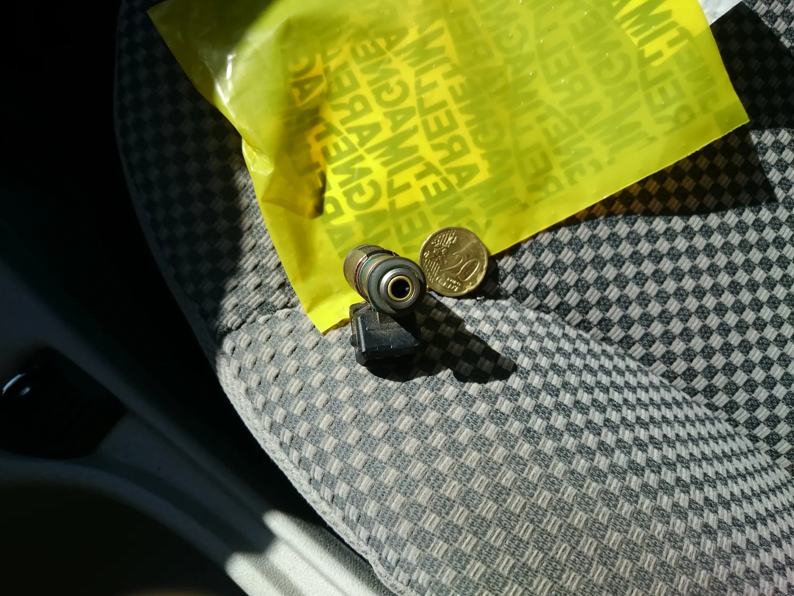 Small fuel-injection component with a sealing O-ring beside a coin and parts packaging