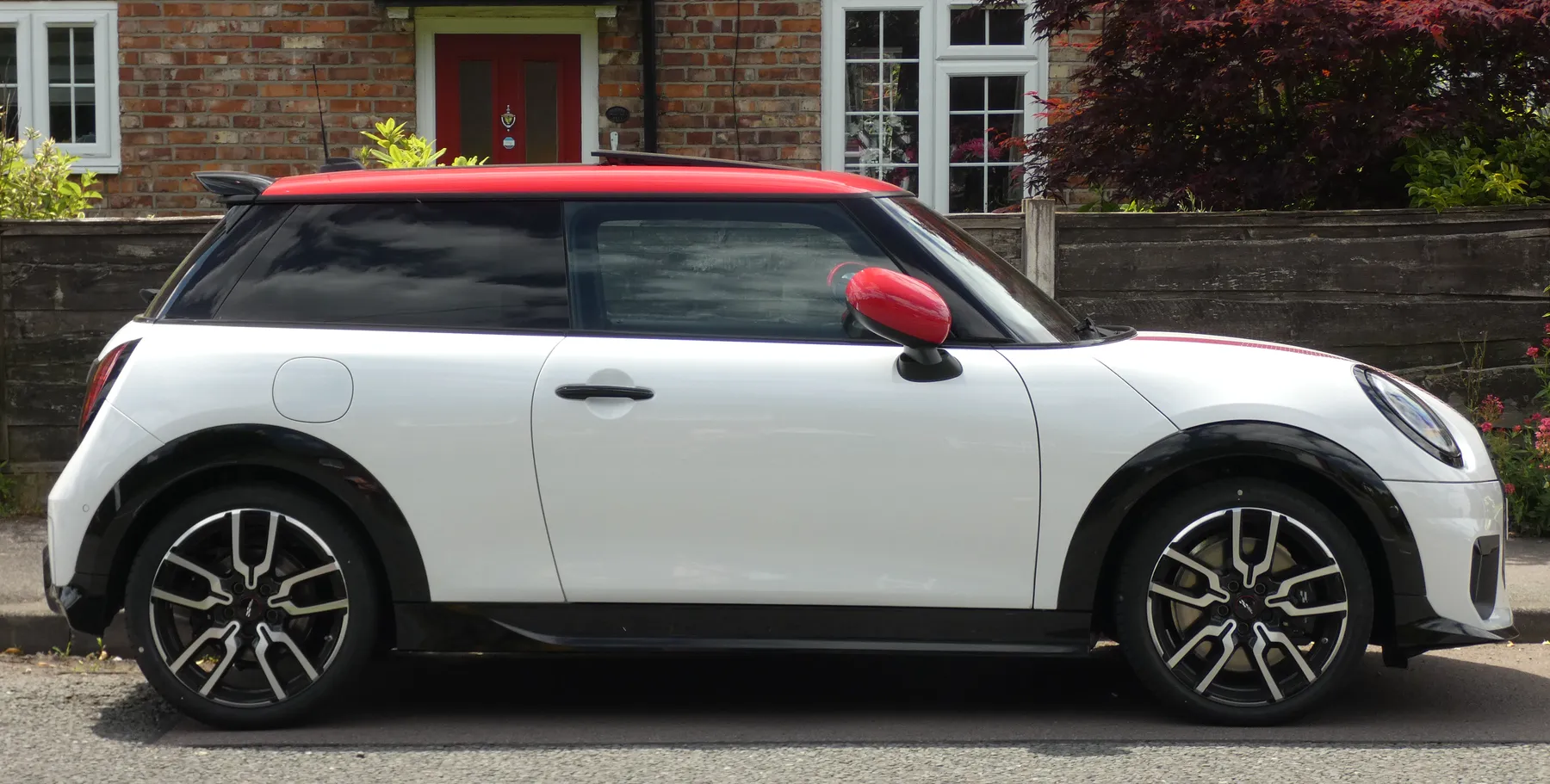 Side view of a white 2024 MINI Cooper Sport C, an F66 two-door, with a short hood, a round headlamp, and a triangular tail lamp