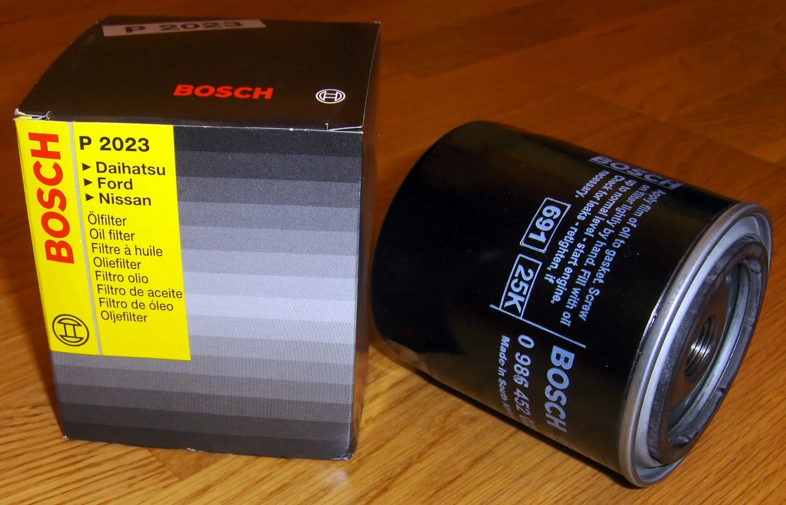 Bosch P20233 spin-on oil filter beside its box on a wood table