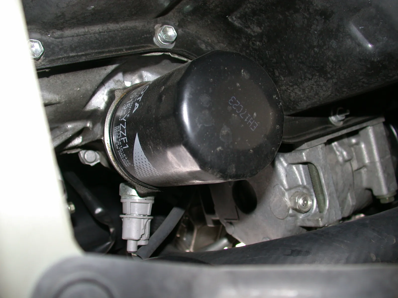 Black spin-on oil filter threaded onto an engine in the bay, sensor plugged into the housing