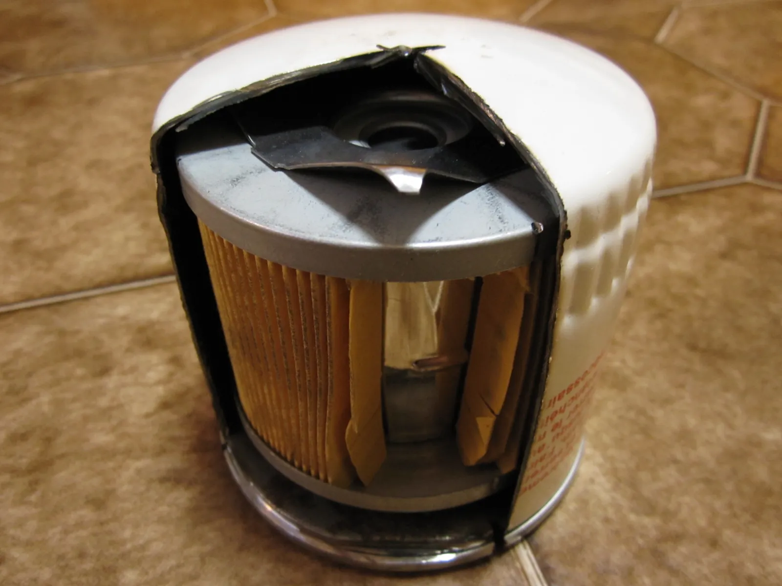 White spin-on oil filter cut away to show pleated media, center tube, and the bypass valve in the lid