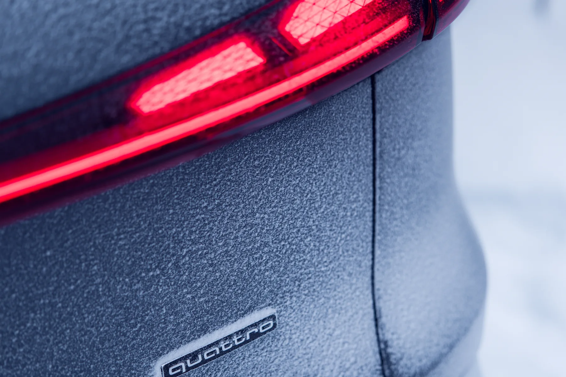 Frost-covered rear corner of a third-generation Audi Q5, showing the red lamp graphic and quattro badge