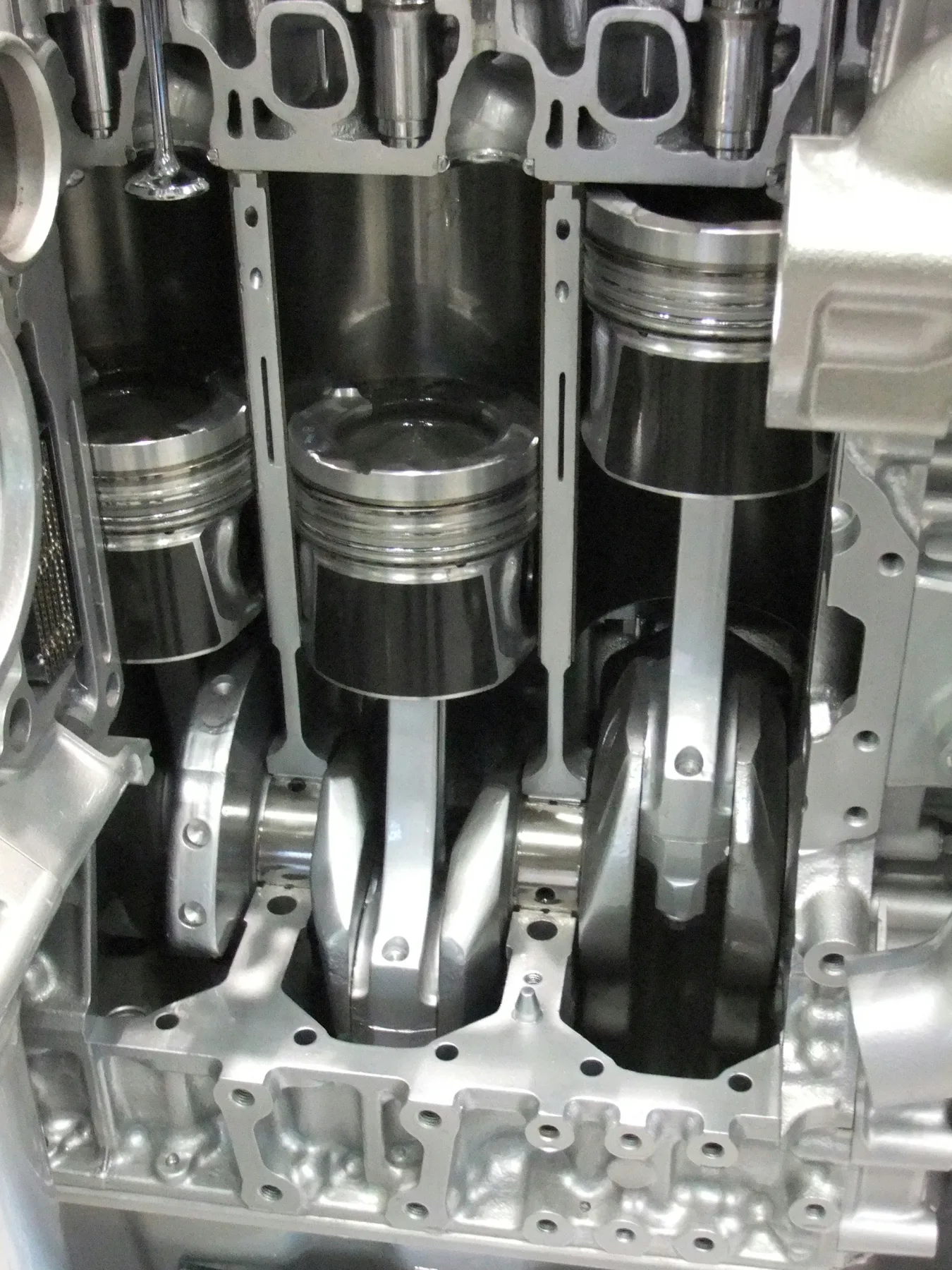 Partial cutaway of an engine showing a piston, connecting rod, and crank throw in one cylinder