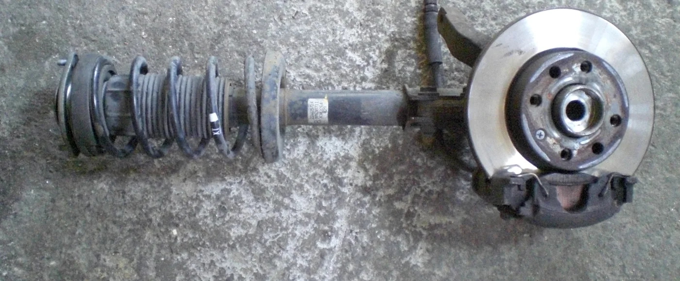 Removed strut assembly with coil spring, damper, knuckle, hub, disc and caliper still attached