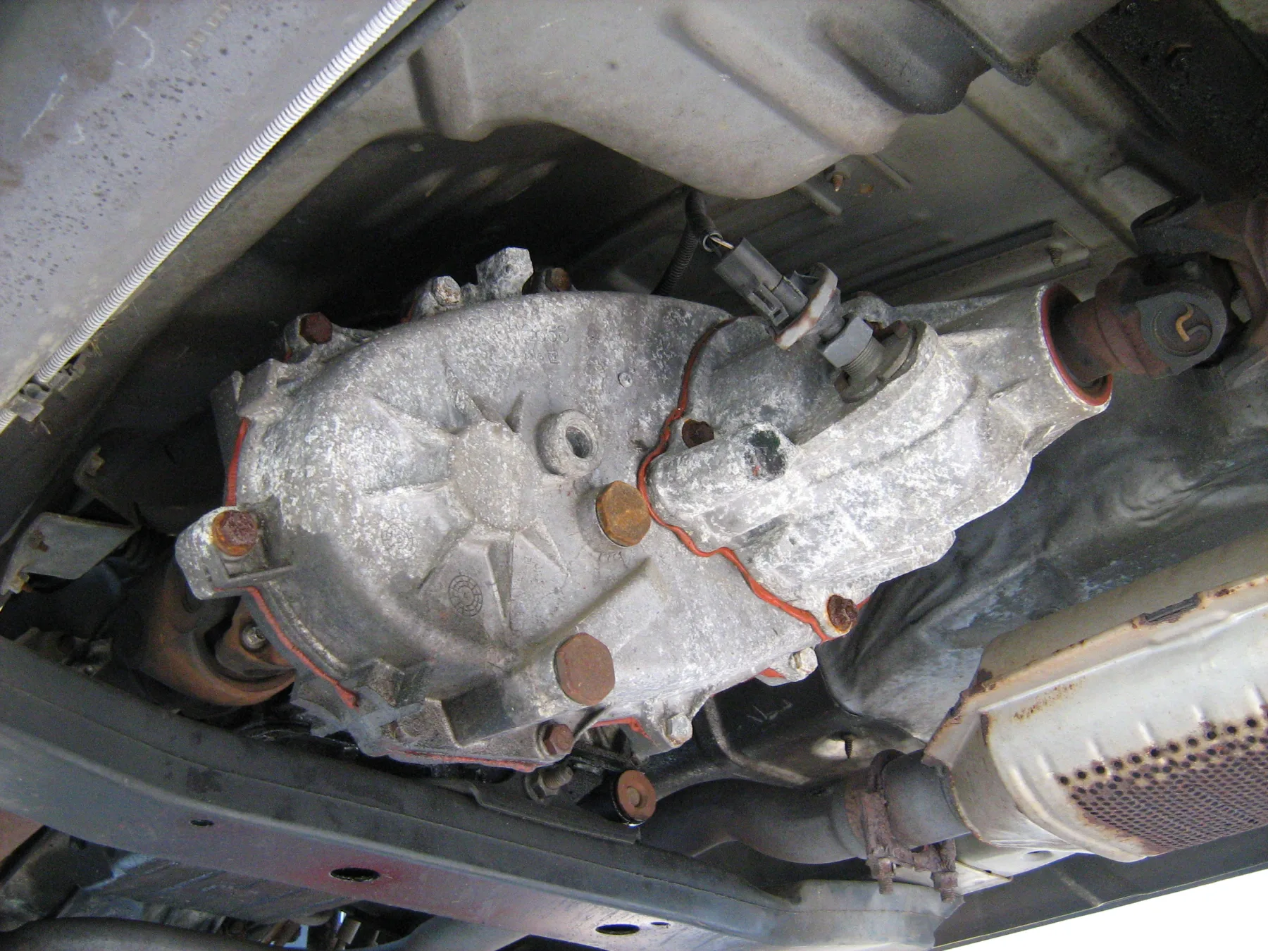 Underside of a 1993 Jeep Grand Cherokee, with the transfer-case housing mounted behind the transmission, the output and propeller shaft, and the exhaust and catalytic converter nearby