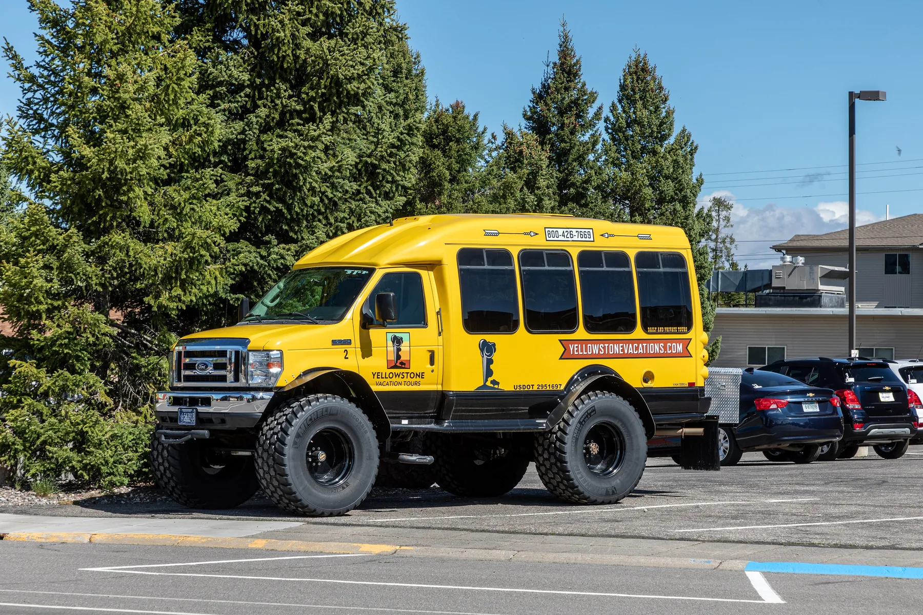 Yellow and white Yellowstone Vacation Tours motor coach parked at the curb